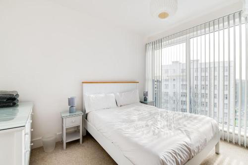 a white bedroom with a bed and a large window at Central Bournemouth Apartment, Balcony, Free Parking in Bournemouth
