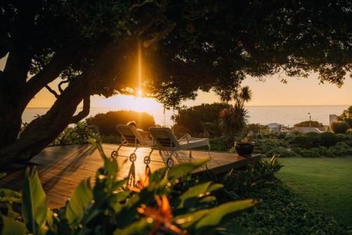 Cape Town的住宿－海景之家酒店，木甲板上摆放着两把椅子,享有日落美景