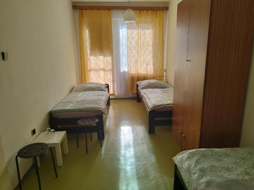 a room with three beds and a table and a window at Ubytovňa KARPATIA in Šaštín
