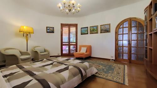 a bedroom with a bed and chairs and a chandelier at Villa Sofia in Terrauzza