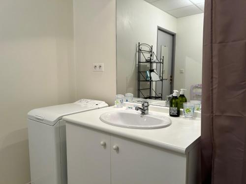 une salle de bain blanche avec un lavabo et un miroir dans l'établissement 489 - Appart T2 surplombant la plage de Caroual., à Erquy