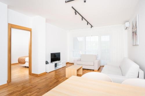 a white living room with a white couch and a tv at Fruške Residences in Vrdnik