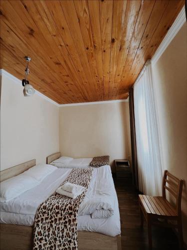 two beds in a room with a wooden ceiling at Guest House Nikala in Mestia