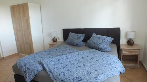 1 dormitorio con 1 cama con manta azul y 2 mesas en Zimmer im Ferienpark Buntspecht, en Pruchten