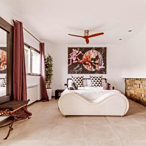 a bedroom with a large white bed and a ceiling fan at Villa La Roca Madrid in Guadarrama