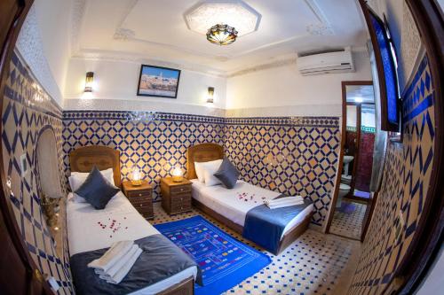 フェズにあるDar Amir Fezのベッド2台と鏡が備わる客室です。