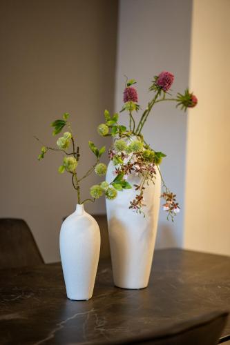 two white vases with flowers in them on a table at Isrentals Haneviim - ApartHotel In City Center in Jerusalem