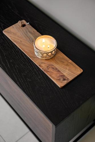 a candle in a bowl on a wooden cutting board at Isrentals Haneviim - ApartHotel In City Center in Jerusalem