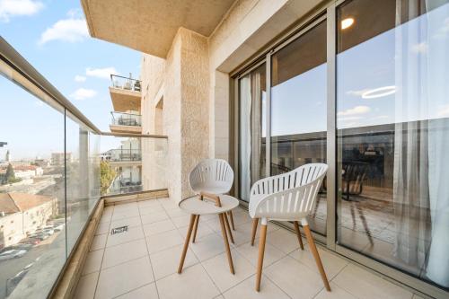 two white chairs on a balcony with windows at Isrentals Haneviim - ApartHotel In City Center in Jerusalem