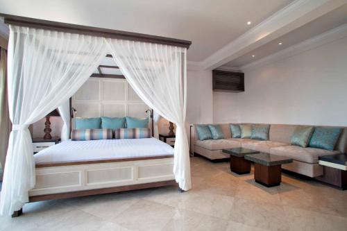 a bedroom with a canopy bed and a couch at Sundara Oceanside Villa in Tanah Lot