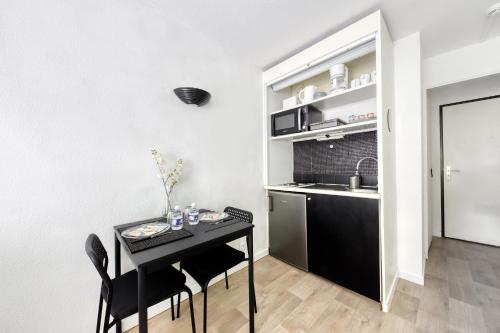 une petite cuisine avec une table et des chaises noires dans l'établissement Studio Paris La Défense, à Courbevoie