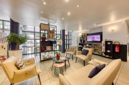 a waiting room with couches and chairs and a tv at ADAGIO Access - PARIS LA DEFENSE in Courbevoie