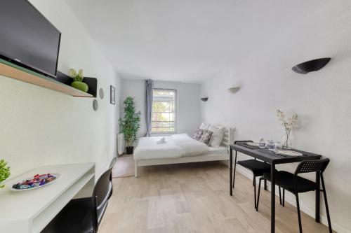 a white living room with a table and a bed at ADAGIO Access - PARIS LA DEFENSE in Courbevoie