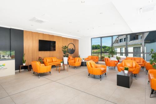 a waiting room with orange chairs and a flat screen tv at Fruške Residences in Vrdnik
