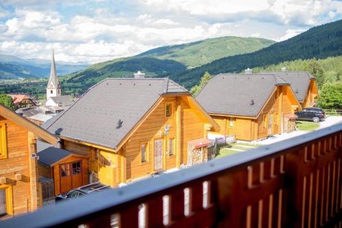 a group of wooden houses with a church in the background at Charmantes Ferienhaus in Sankt Margarethen Im Lungau mit Kleinem Garten und Bergblick in Sankt Margarethen im Lungau