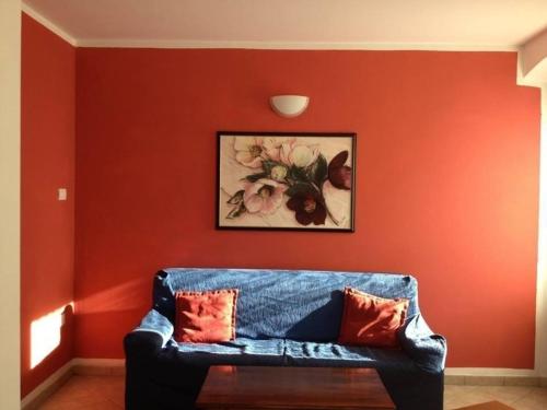 Sofá azul en una habitación con pared roja en Schönes Appartement in Tiarno Di Sotto mit Garten, en Tiarno di Sotto