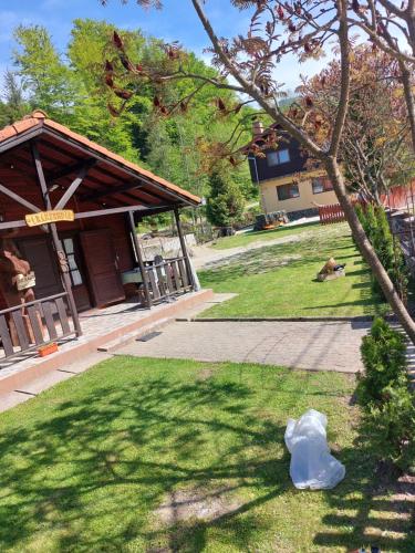 a small building with a tree in the grass at Dor de Munte Transfăgarasan in Cîrţişoara