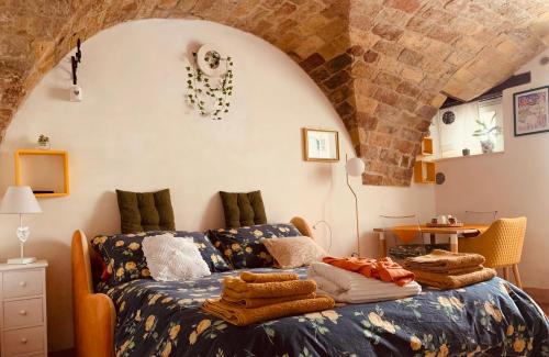 Un dormitorio con una cama con mantas. en Merli e Merletti - affittacamere- monolocale luminoso e indipendente nel cuore di Offida, en Offida