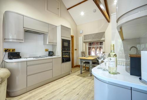 a kitchen with white cabinets and a table with wine glasses at The Apartment Garth House in Brampton