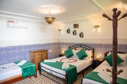 two beds in a room with blue and white tiles at Dar Amir Fez in Fès
