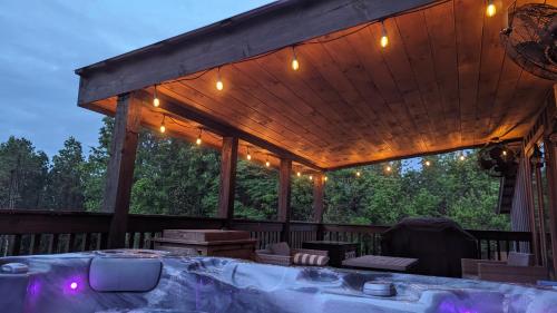a wooden deck with a table and lights on it at Enjoy Ozark History in Style! in Hasty