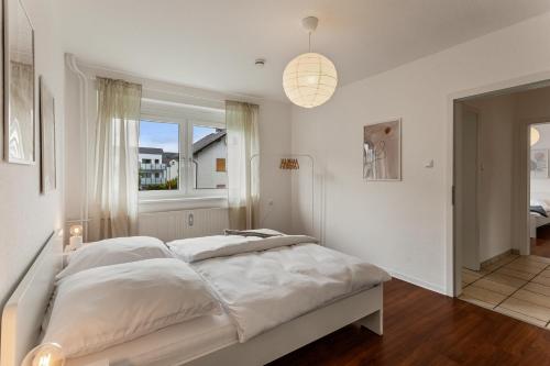 a white bedroom with a large bed with a window at LAHNTALER 6 Gäste, WLAN, Netflix, Bahnhofsnah in Sterzhausen