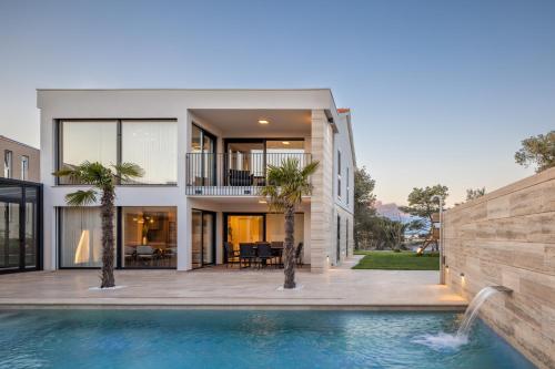 a house with a swimming pool in front of a house at Salt and Stone Villa in Nin