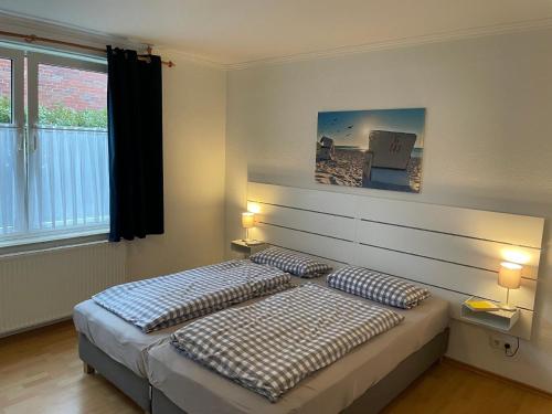 een slaapkamer met een bed met 2 kussens erop bij Großzügige Ferienwohnung mit Privatgarten im Nordseebad Carolinensiel in Wittmund