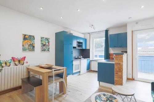 une cuisine avec des armoires bleues et une table et des chaises dans l'établissement Oasis tropicale a Cleguerec, à Cléguérec