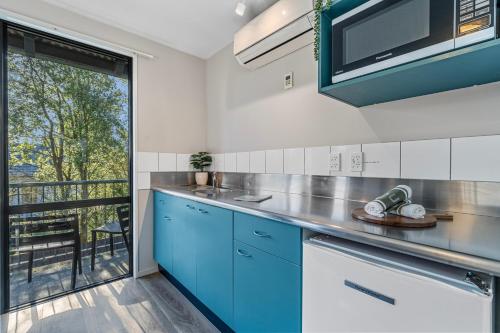 a kitchen with blue cabinets and a balcony at Tasman Holiday Parks - Christchurch in Christchurch