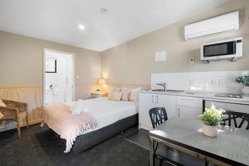 a bedroom with a bed and a kitchen with a table at Tasman Holiday Parks - Christchurch in Christchurch