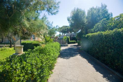 a walkway through a yard with bushes and trees at vento di mare in Bari