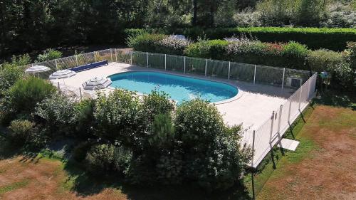 une piscine dans un jardin avec une clôture dans l'établissement Domaine du grand roc- Gîte 1-La mésange, à Saint-Saud-Lacoussière
