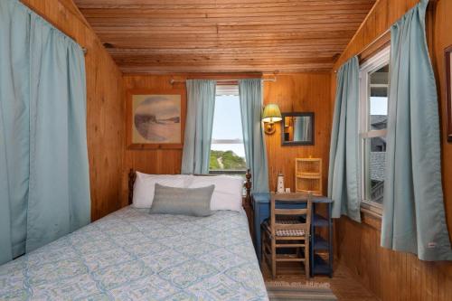 a bedroom with a bed and a table and a window at NH222 Island Dancer in Nags Head