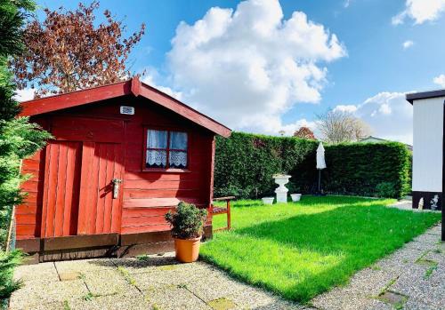 a red shed in a yard with green grass at Familienfreundlisches Ferienhaus "Angel mit Garten und Terrasse am Ijsselmeer Grote Vliet Niederlande in Wervershoof