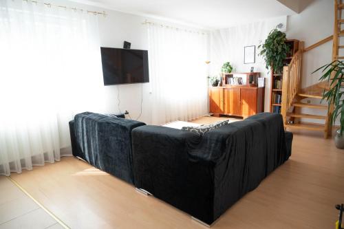 um sofá preto sentado numa sala de estar em Kamień Pomorski Homely House em Kamień Pomorski