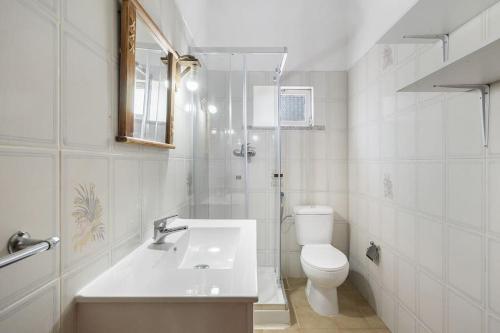 een witte badkamer met een toilet en een wastafel bij Villa Oasis - Pool & Garden in Santa Marta