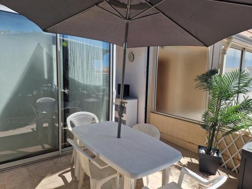 une table et des chaises avec un parasol sur un balcon dans l'établissement Agréable appartement 3 Personnes Port La Nouvelle RDC et petit jardin, à Port-la-Nouvelle