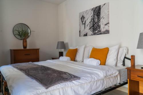 Un dormitorio con una cama con sábanas blancas y almohadas naranjas. en Lovely Penthouse in Gzira, en Il-Gżira