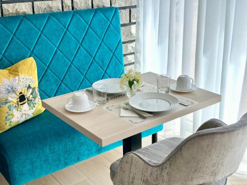 una mesa con platos y servilletas en una silla azul en Éllő Residence, en Veszprém