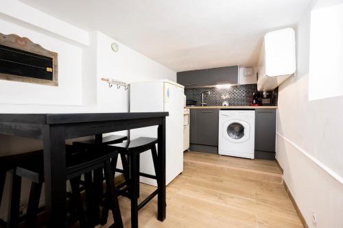 une petite cuisine avec une table noire et une laveuse et une sécheuse dans l'établissement Escapade au Roc de Picchu, à Étretat