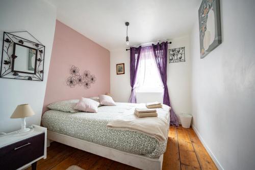 een slaapkamer met een bed en een raam met paarse gordijnen bij Escapade au Roc de Picchu in Étretat