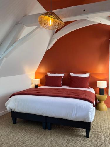 a bedroom with a bed with an orange wall at Le Clos Gabrielle in Châtellerault