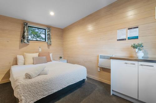 a bedroom with a white bed and wooden walls at Tasman Holiday Parks - Christchurch in Christchurch