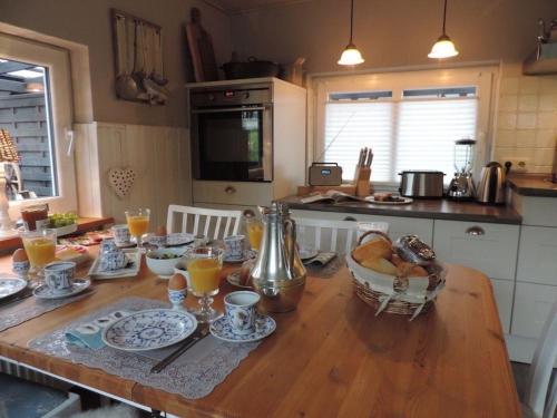 eine Küche mit einem Holztisch mit Speisen und Orangensaft in der Unterkunft Liebevoll eingerichtetes Landhaus mit Charme und Seele und wunderschönem Garten in Hage