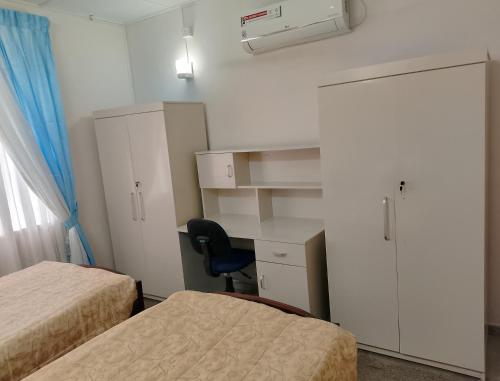 a room with two beds and a desk and a cabinet at Serenity Villa in Divulpitiya