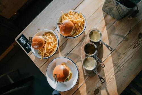 three plates with sandwiches and french fries on a wooden table at Tapnell Manor At Tapnell Farm in Yarmouth