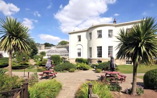 a white house with picnic tables and palm trees at Owston Hall Hotel in Doncaster