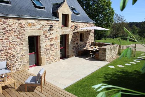 a patio with a table and an umbrella next to a building at La Chaumière - Nature et SPA privé in Béganne