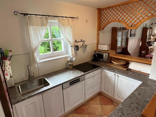 eine Küche mit weißen Schränken, einem Waschbecken und einem Fenster in der Unterkunft ALPHA in Badacsonytördemic